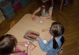 dziewczynki przy stolikach kolorują krople wody
