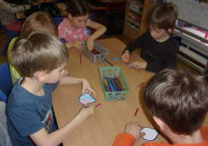 dzieci kolorują krople wody przy stolikach