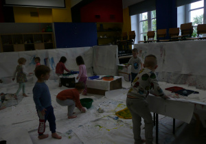 dzieci podczas malowania farbami na dużych białych arkuszach papieru