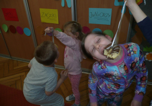 dzieci w parach próbują zjeść pączka zawieszonego na nitce