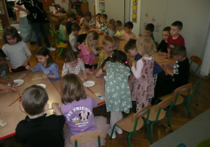 dzieci przy stolikach wykonują zakładki do książek