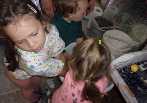dzieci przy stoliczkach podczas warsztatów z gliny