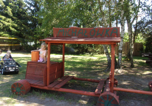 dziewczynka na drewnianym traktorku z napisem "Michałówka"
