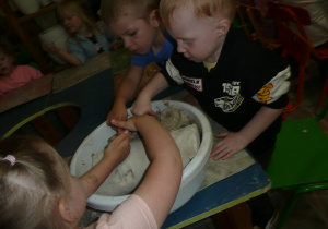 dzieci pobierają glinę z miski