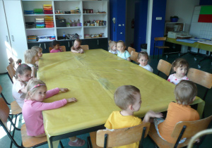 dzieci siedzą przy stole nakrytym folią