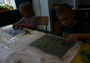 dzieci przekładają liście na wyciśniętą masę papierową