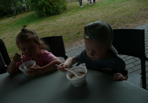 dzieci jedzą zupę przy okrągłych stołach