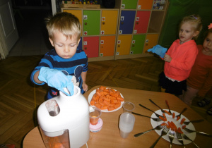 dzieci ustawione w kolejce robią sok z marchwi