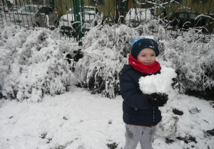 chłopczyk w granatowej kurtce i czerwonym szaliku epi kulę śniegową
