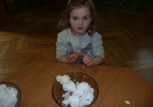 dziewczynka przy stoliczku lepi bałwanka ze śniegu na talerzu