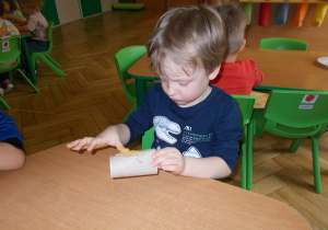 chłopczyk smaruje rolkę po papierze masłem orzechowym