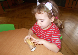 dziewczynka smaruje rolkę po papierze masłem orzechowym