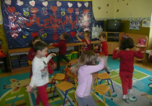 Zabawa z krzesełkami w grupie Żaczki - dzieci ubrane na czerwono