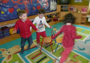 Zabawa z krzesełkami w grupie Żaczki - dzieci ubrane na czerwono