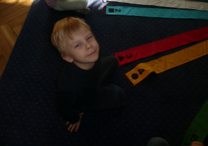 chłopiec siedzi uśmiechnięty na dywanie podczas zajęć logorytmicznych