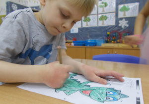 Chłopiec koloruje postać dinozaura Dinusia