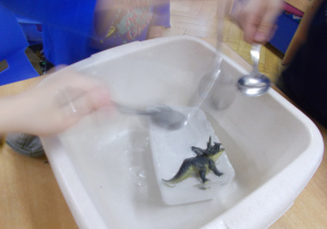 zdjęcie przedstawia figurkę dinozaura wwydobytą przez juniorów z kostki lodu