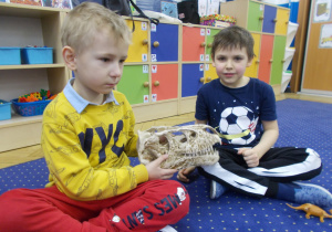 dzieci w kole oglądają czaszkę dinozaura