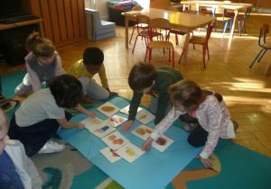 dzieci na dywanie układają piramidę zdrowia z otrzymanych wcześniej ilustracji