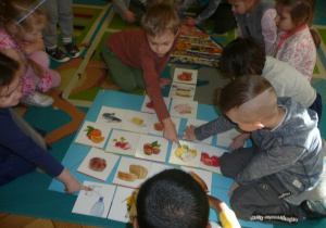 dzieci na dywanie układają piramidę zdrowia z otrzymanych wcześniej ilustracji