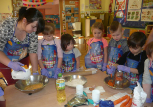 dzieci w kole ptzy stoliku podczas przygotowywania ciasta marchewkowego