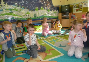 dzieci na dywanie jedzą marchewkę