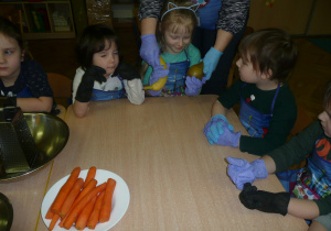 dzieci w kole przy stolikach rozpoznają owoce po dotyku