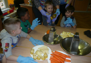 dzieci w kole przy stolikach rozpoznają owoce po dotyku