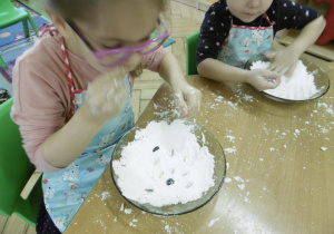 dzieci na swoich miejscach przy stoliczkach bawią się przygotowanym wcześniej sztucznym śniegiem