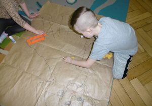 dziewczynka z chłopcem na szarym papierze przykleją pierwsze kolorowe elementy