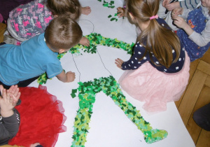 dzieci z grupy Tuptusie przyklejają elementy z bibuły na postac Pani Wiosny