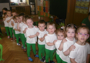 Tuptusie w zielonych spodenkach i białych bluzeczkach udają się na zawody sportowe na salę gimnstycznąe