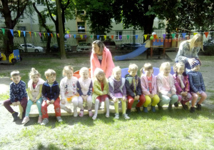 Smyki na ławeczce w ogrodzie przedszkolnym w oczekiwaniu na atrakccje związane z Dniem Dziecka