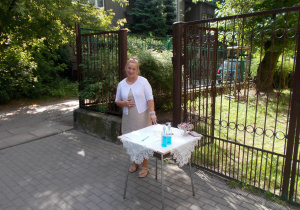 Ciocia Beatka przy stoliczku przy wejściu do ogrodu przedszkolnego