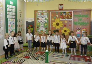 Pasowane na Przedszkolaków dzieci ustawione w półkolu śpiewaja piosenkę