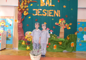 dwaj chłopcy w strojach jesiennych na tle dekoracji z okazji balu jesieni