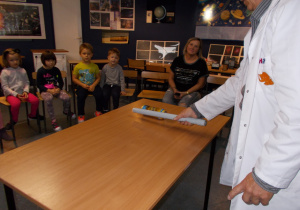 Żaczki i Juniorzy na krzesełkach oglądają eksperymenty w Centrum zajęć pozaszkolnych „Planetarium”