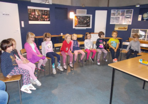 Żaczki i Juniorzy na krzesełkach oglądają eksperymenty w Centrum zajęć pozaszkolnych „Planetarium”