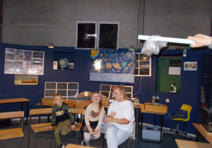 Ciocia Betaka z chłopcem i dziewczynką oglądają eksperymenty w Centrum zajęć pozaszkolnych „Planetarium”