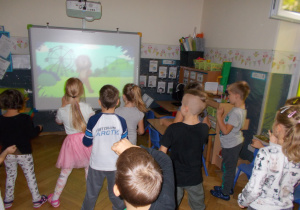 Juniorzy wykonują ćwiczenia stojąc naprzeciwko tablicy interaktywnej