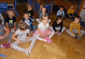 Juniorzy wykonują ćwiczenia siedząc naprzeciwko tablicy interaktywnej