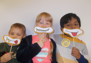 trije dzieci z maskami z narysowanymi minami