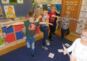 Juniorzy w swojej sali wykonują ćwiczenia gimnastyczne pokazane na tablicy interaktywnej