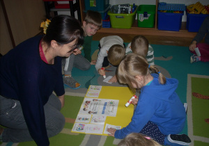 dzieci siedząc na dywanie przyklejają obrazki