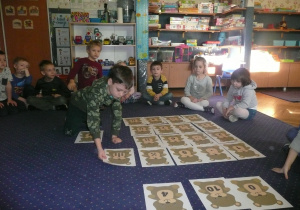 Juniorzy układają misie na dywanie