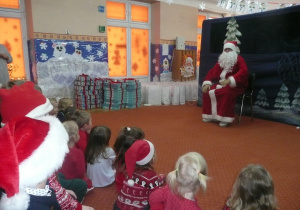 Mikołaj na tle dekoracji zimowej oraz prezentów dla przedszkolaków