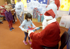dziewczynka odbiera prezent od Św. Mikołaja