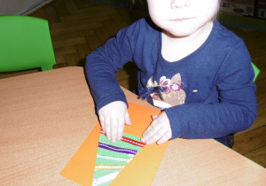 dziewczynka przy stoliku wykonuje świąteczną kartkę