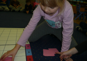 dziewczynka na dywanie układa kartoniki wg określonych kodów
