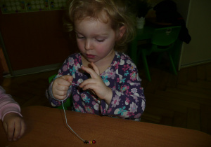 dziewczynka nawleka koralik na sznureczek